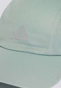 Gorra verde clara hecha de una tela texturizada, con un logo de Adidas en gris y un pico estructurado. Los detalles reflectantes añaden contraste.
