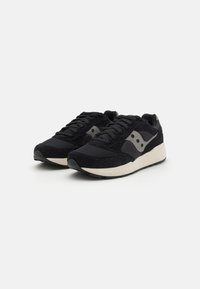 Chaussures de sport noires avec un mélange de matériaux en daim et en mesh. Design léger avec des semelles en caoutchouc crème contrastantes et des accents sur les côtés.