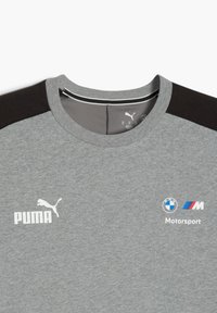 Grå T-shirt med Puma og BMW Motorsport logoer. Sorte skulderdetaljer forbedrer det sporty design. Simpelt og moderne stil.