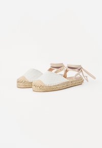 Weiße Espadrilles mit einem strukturierten Stoff-Obermaterial, einer Jutesohlen und Knöchelbandagen für sicheren Halt. Abgerundete Zehenform.