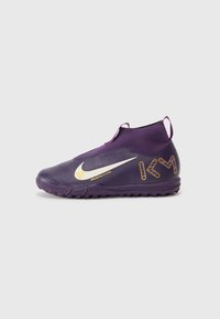 Scarpa sportiva viola con design alto alla caviglia, upper testurizzato, swoosh Nike bianco e dettagli dorati sul lato e sul tallone. Suola in gomma nera.