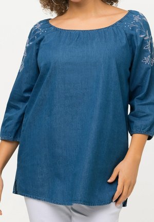 Blauwe denim blouse met een brede halslijn, driekwart mouwen en bloemrijke borduursels op de schouders. Heeft een ontspannen pasvorm en zijsplitten.