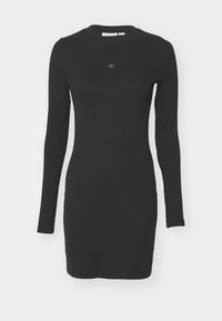 Black long-sleeve dress in ribbed texture with a fitted silhouette. Features a round neckline and a small logo patch in the center.