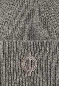 Gorro de punto gris con textura acanalada horizontal y un parche de logotipo circular en un color contrastante en la parte frontal.