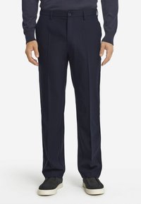 Granatowe spodnie w kant o klasycznym kroju, wykonane z gładkiego materiału. Posiadają zapięcie na guziki oraz boczne kieszenie, zestawione z czarnymi butami wsuwanymi.