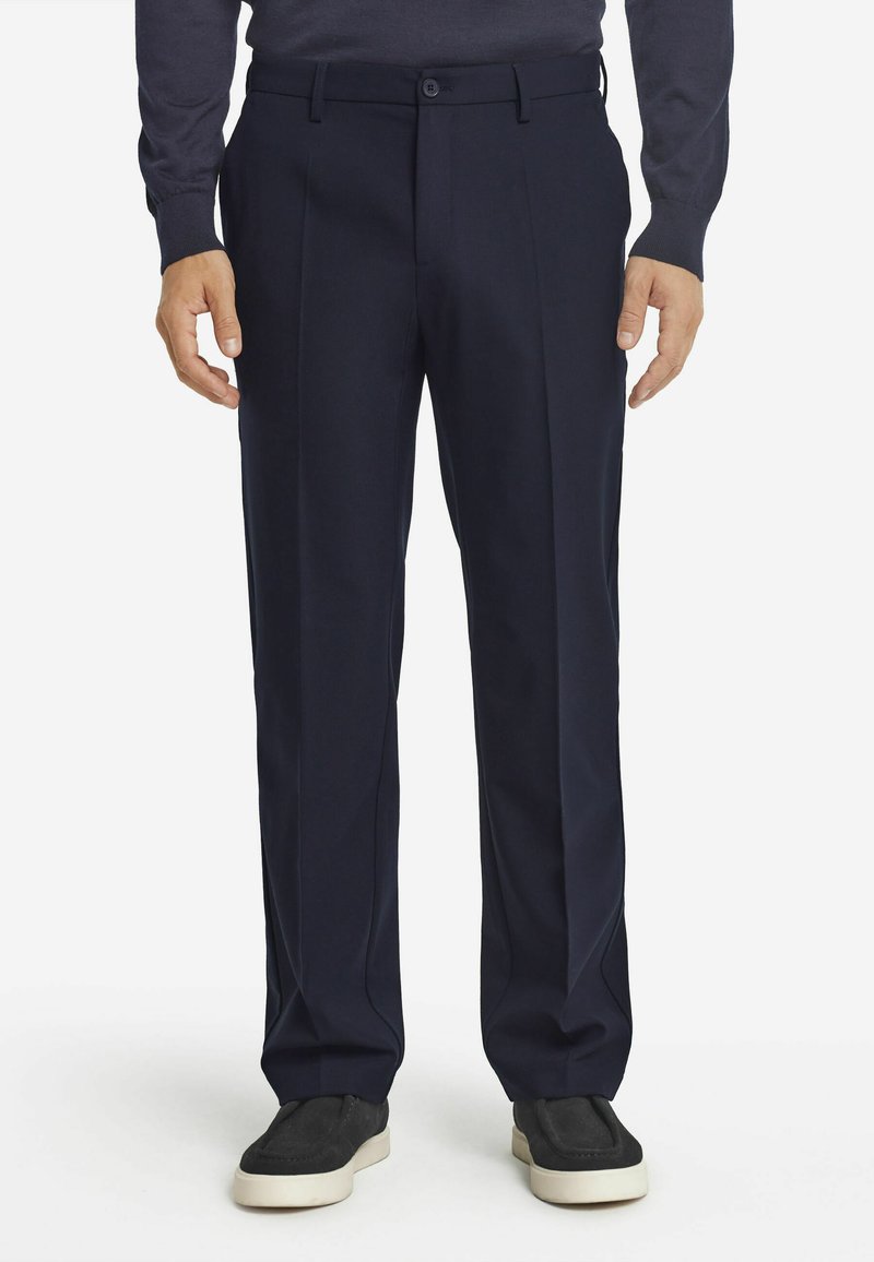 Granatowe spodnie w kant o klasycznym kroju, wykonane z gładkiego materiału. Posiadają zapięcie na guziki oraz boczne kieszenie, zestawione z czarnymi butami wsuwanymi.