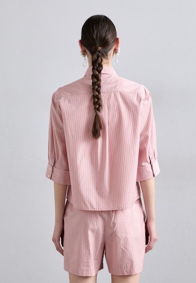 Short-sleeve pink striped shirt paired with matching shorts, featuring a relaxed fit, button accents, and a back pocket detail.