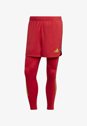 Red athletic shorts with a gray accent, paired with tight-fitting red leggings featuring yellow stripe detailing on the sides.