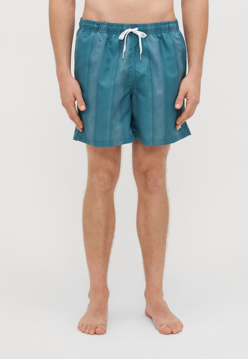 Plávacie šortky v tyrkysovej farbe, s ľahkým dizajnom, elastickým pásom s bielou šnúrkou a bočnými rozparkami pre ľahší pohyb.