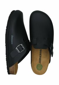 Black clogs made from smooth plastic with a cork footbed, featuring a buckle strap, rounded toe, and embossed logo on the side.