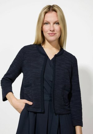 Dunkelblauer, strukturierten Cardigan mit einem cropped Design, Rundhalsausschnitt, drei Viertelärmeln, vorderen Taschen und einem dezenten Zickzackmuster.