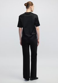 Top negro de satén de manga corta y pantalones negros ajustados, con una textura suave y un diseño simple y moderno.
