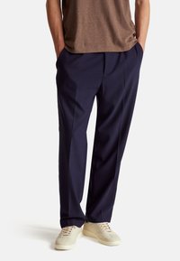 Námornické kalhoty s rovný fit a jemným záhybem, vyrobené z texturované tkaniny, spárované s béžovými teniskami.