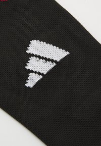 Tecido preto com um logotipo triangular branco e texturizado que apresenta três formas empilhadas. O material parece ser tecido com um acabamento suave.