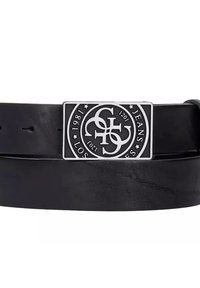 Cinturón de cuero negro con una hebilla rectangular de metal plateado que presenta un diseño de logo y texto. El cinturón tiene una textura suave y múltiples agujeros.