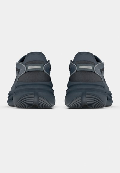 Σκούρα γκρι αθλητικά παπούτσια με υφαντό υλικό στο επάνω μέρος, μαλακή σόλα και ανακλαστικές λεπτομέρειες. Διαθέτουν επένδυση στη φτέρνα και καμπυλωτό σχεδιασμό.