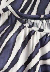Top a maniche corte con stampa zebra in blu navy scuro e bianco, realizzato in tessuto leggero, con scollatura rotonda e dettagli arricciati.