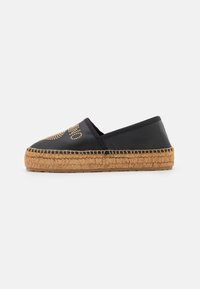 Black espadrille with a woven jute sole, featuring metallic studs on the upper, round toe, and elasticized sides for easy slip-on wear.