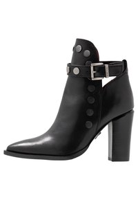 Černá kožená kotníková bota s špičatou špičkou, stříbrnými kovovými doplňky a přezkou. Na vnější straně zdobená dekorativními kovovými nýty.