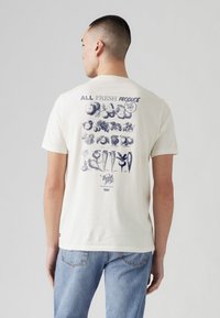 White cotton t-shirt with a graphic of various fruits and vegetables in navy blue on the back, text "ALL FRESH PRODUCE" above the design.