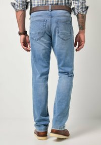 Vaqueros de mezclilla azul claro con corte de pierna recta, diseño de cinco bolsillos y cinturón de cuero marrón. La tela tiene una textura suave y desgastada.