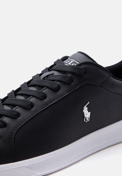 Μαύρο δερμάτινο αθλητικό παπούτσι με μαύρα κορδόνια, λευκή σόλα και ασημένιο λογότυπο Polo Ralph Lauren στο πλάι.