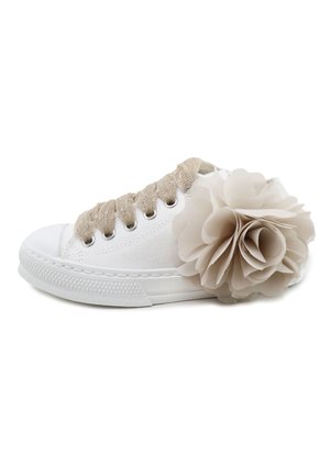 Zapatilla de lona blanca con cordones beige y una gran flor de tela beige pegada cerca del talón sobre un fondo blanco.