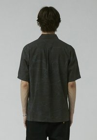 Short-sleeve shirt in dark gray with abstract pattern, button-down collar, soft texture, and loose fit. Features a central back pleat.