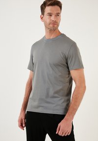 Šedé bavlněné tričko s kulatým výstřihem, krátkými rukávy a hladkou texturou. Disponuje standardním střihem a minimalistickým designem.