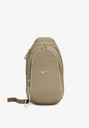 Beżowa torba na jedno ramię Nike z przednią kieszenią na suwak, główną komorą i regulowanym pojedynczym paskiem na ramię.