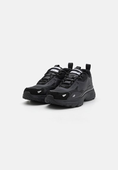 Chaussures de sport noires avec un mélange de matériaux texturés, y compris du daim et des matières synthétiques. Avec une semelle en caoutchouc épaisse, des panneaux en maille et des accents réfléchissants.