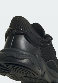 Černé sportovní boty s textilním svrškem, hladkými koženými akcenty a odolnou gumovou podrážkou. Mezi funkce patří poutko a elegantní design.