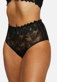 Slip neri a vita alta in pizzo, caratterizzati da intricati motivi floreali e bordi scallopati, con pannelli laterali per un ulteriore dettaglio.