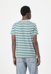 T-shirt rayé blanc avec des rayures horizontales teal et bleu marine. Manches courtes, col rond, coupe décontractée et texture de tissu douce.