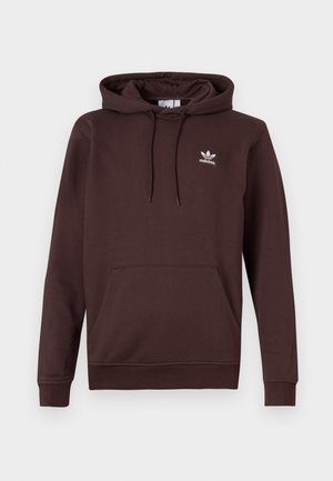 Tamsiai rudas Adidas gobtuvu džemperis su priekinėmis kišenėmis ir baltu trefoil logotipu kairiajame krūtinės šone, pavaizduotas ant neutralios fono.