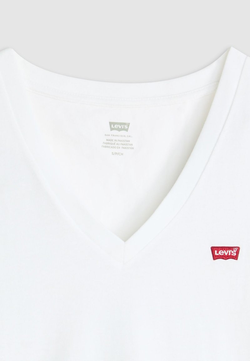 Weißes Baumwoll-T-Shirt mit V-Ausschnitt und rotem Levi's-Logo-Patch links vom Ausschnitt. Weiche Textur mit klassischer Passform.
