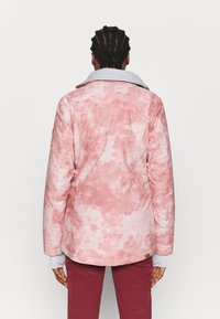 Rosa Batik-Jacke mit einem hellgrauen Kragen, geknöpften Manschetten und einer strukturierten Oberfläche. Verfügt über ein Markenschild an der unteren Seite in der Nähe des Saums.