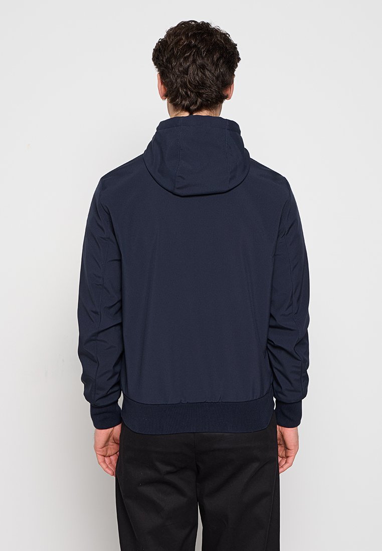 Giacca con cappuccio blu navy realizzata in tessuto leggero, con vita aderente e polsini a costine, caratterizzata da una texture morbida e un design minimale.