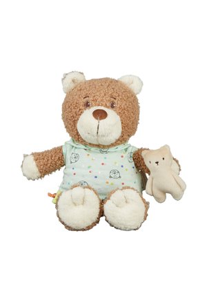 Brauner, lockiger Teddybär mit einem hellgrünen, gepunkteten Hemd, der auf weißem Hintergrund einen kleinen beigen Teddybär-Plüsch hält.