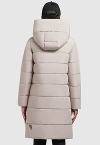 Manteau doudoune gris clair avec des coutures horizontales, une grande capuche et un patch logo au bas, avec une texture lisse et brillante.