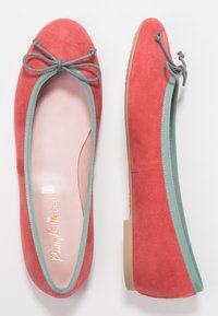 Korallfärgade mockaballerinaskor med ljusblå kant och matchande rosettdetalj. Mjuk inredning med guld-logotyp på innersulan. Platt, flexibel sula.