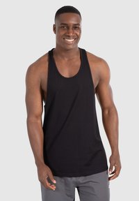 Camiseta sin mangas negra de algodón, con amplios escote y un corte holgado, combinada con pantalones cortos grises. Diseño simple.