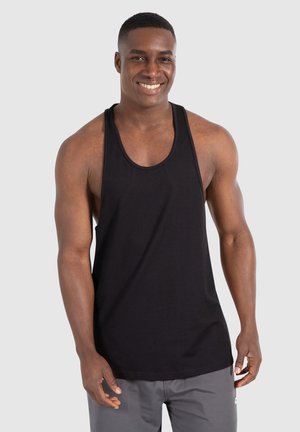 Canotta nera in cotone, con ampie aperture per le braccia, scollatura arrotondata e una vestibilità ampia, abbinata a pantaloni corti grigi. Design semplice.