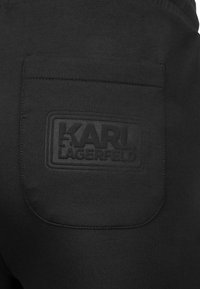 Czarne bawełniane spodnie dresowe z fakturowaną naszywką z logo "KARL LAGERFELD" wytłoczonym na tylnej kieszeni, gładka powierzchnia tkaniny.