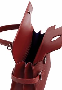 Bolso de cuero en rojo oscuro con un exterior texturizado. Presenta un compartimento con cremallera y un cierre magnético. El interior está forrado en tela azul.