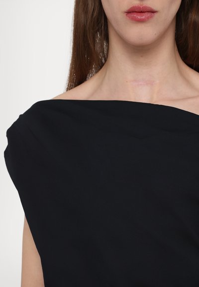Zwarte off-the-shoulder top met een gladde textuur; heeft een brede halslijn en een minimalistisch ontwerp. Geen zichtbare patroontjes of hardware.