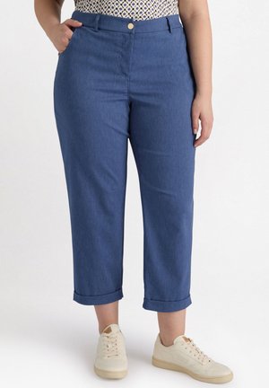 Blauwe denim cropped broek met een soepele textuur, voorzakken, een knoopsluiting en opgerolde mouwen, gecombineerd met crèmekleurige sneakers.