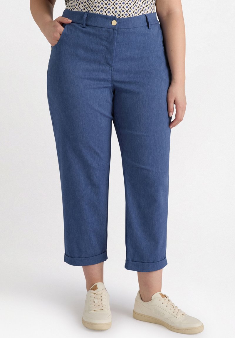 Blauwe denim cropped broek met een soepele textuur, voorzakken, een knoopsluiting en opgerolde mouwen, gecombineerd met crèmekleurige sneakers.