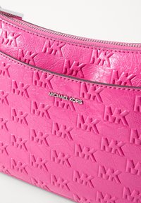 Borsa in pelle rosa con motivo in rilievo "MK", cerniera in tonalità argento e superficie liscia; presenta una placca con il logo sul davanti.
