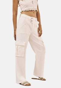 Pantalones cargo blancos con un corte holgado, que cuentan con grandes bolsillos laterales, cierre de botón y una cintura plana. Material de algodón suave, corte recto.